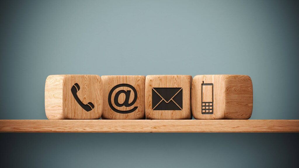 Wooden blocks with landline, email, postal mail and cell phone icons